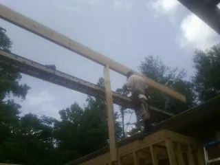 Carpenter setting a ridge beam over a new addition frame — Ice Dam Removal by Roofing Brothers in North Scituate