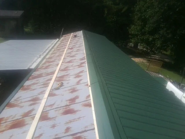 Old rusted panels beside newly installed green metal roofing — Wind Damage Roof Repair by Roofing Brothers in North Scituate