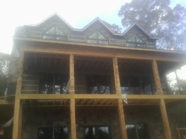 Dormers and porch framing on a large log home under construction — Roof Coating work by our crew in North Scituate