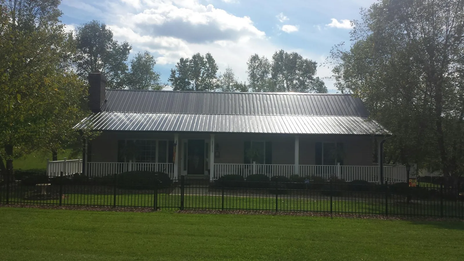 Gray metal roof on a brick ranch with a full width front porch — Gutter Guard Installation work by our crew in North Scituate