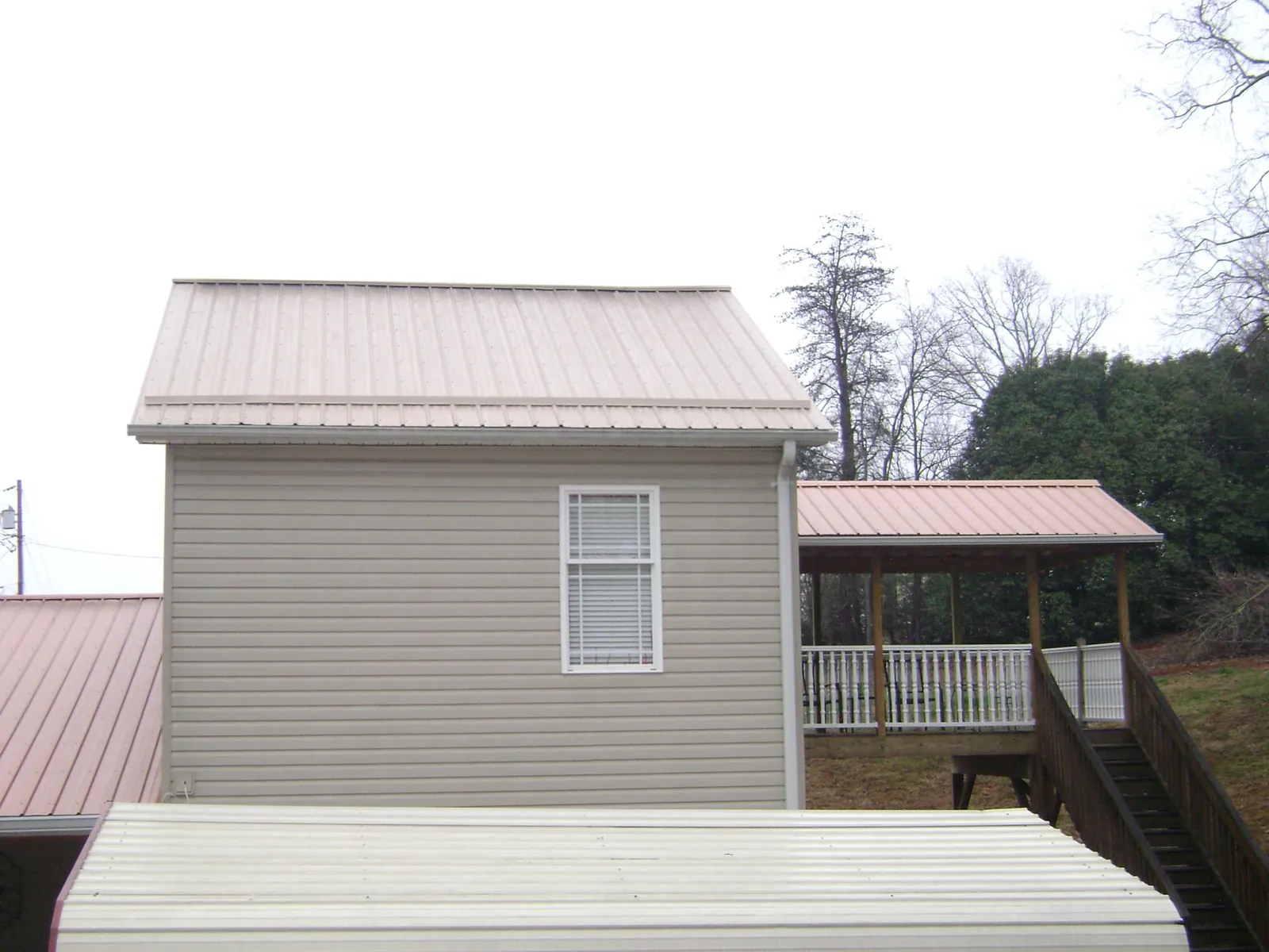 Tan metal roofs on a two story addition and attached porch, from a Roof Replacement job in North Scituate