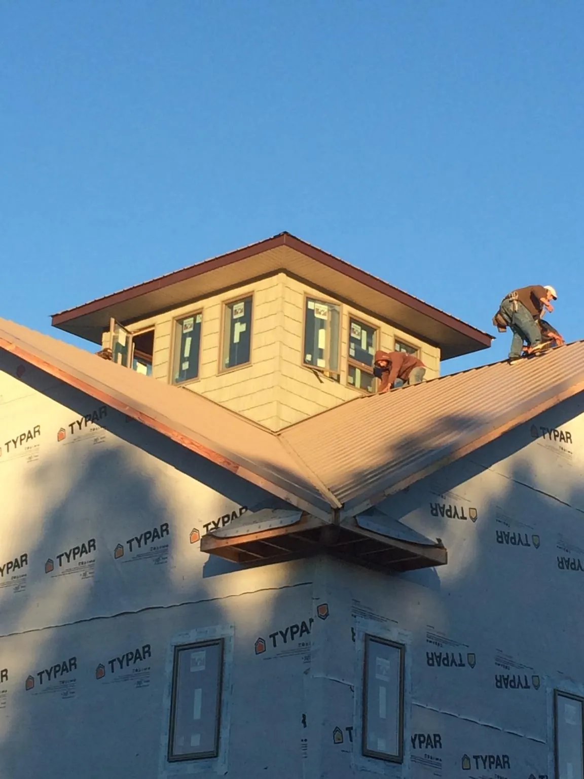 Roofers working around a rooftop cupola on a new metal roof at sunset — Roof Waterproofing in North Scituate by Roofing Brothers